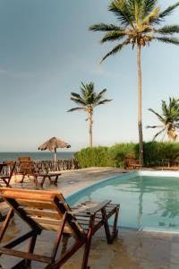 a pool with chairs and palm trees on the beach at Pousada Recanto da Mãezinha in Beberibe