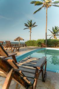 a swimming pool with chairs and palm trees next to the ocean at Pousada Recanto da Mãezinha in Beberibe