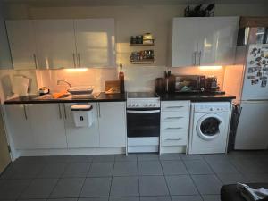 a small kitchen with white cabinets and a dishwasher at Lovely room in Chelsea in London