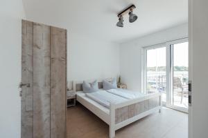 a white bedroom with a bed and a large window at Exklusive Ferienwohnungen an der Havel in Werder