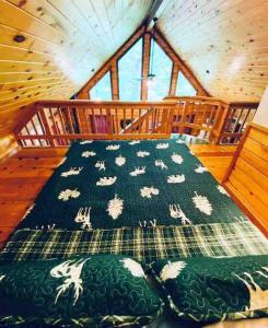a bed in a cabin with a blanket with sheep on it at The Loft at Bear Mountain log cabins in Eureka Springs