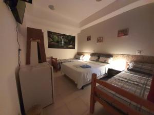 Un dormitorio con dos camas y un refrigerador en él. en Albergue Rio Vermelho, en Salvador