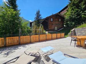 eine Terrasse mit Stühlen, einem Tisch und einem Haus in der Unterkunft Riverside 1st Floor South in Saas-Fee