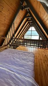 Cama en habitación de madera con ventana grande en Garvela Bungalow, en Artvin