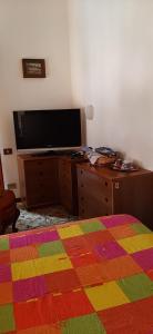 1 dormitorio con TV y manta colorida en Affitta stanza da Paola INTRA Lago, en Intra