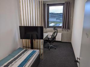Schlafzimmer mit einem Bett, einem Schreibtisch und einem TV in der Unterkunft Business-Motel, Night-Checkin, Breakfast 2go, XL-Parking, free WiFi in Heimsheim