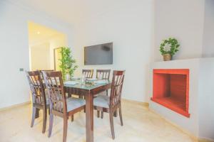 uma sala de jantar com uma mesa e cadeiras e uma lareira em lovely 2 bedroom vacation home with pool/beach em Skhirat