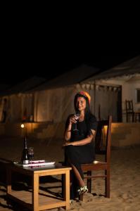 Eine Frau, die auf einem Stuhl mit einem Glas Wein sitzt. in der Unterkunft Sky View in Jaisalmer