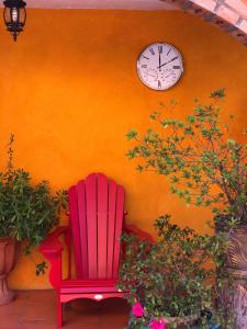 uma cadeira vermelha sentada em frente a uma parede com um relógio em Hotel JADE em Mesa Colorada
