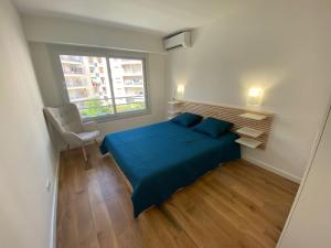 een slaapkamer met een blauw bed en een raam bij Renovated 4 room Apartment-Parking next door and Beach at 700m in Antibes