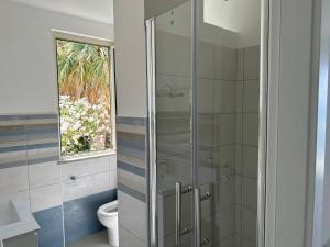 a bathroom with a shower with a toilet and a window at EmmeBi Appartamenti in Acquedolci