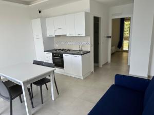 a kitchen with white cabinets and a table and a blue couch at EmmeBi Appartamenti in Acquedolci +54 photos