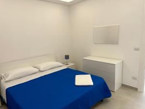 a white bedroom with a blue bed and a desk at EmmeBi Appartamenti in Acquedolci