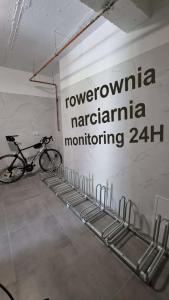 a bike parked next to a wall with a sign at nowe apartamenty nad Górskim Potokiem w Willi Sowiej rowerownia monitorowana in Stronie Śląskie