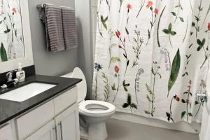 baño con aseo y cortina de ducha con flores en Luxury 1 Bedroom Apt in Plaza Midwood- Fast WiFi, en Charlotte