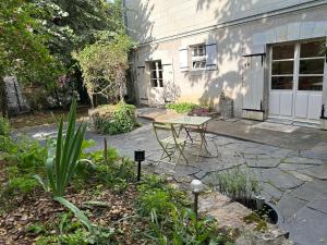 un patio con una mesa frente a una casa en Appartement avec jardin Villeveque 