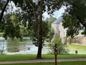 een teken in het gras bij een waterlichaam bij Appartement avec jardin Villeveque 