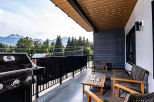 a balcony with a grill and a table and chairs at Northern Exposure by Revelstoke Vacations in Revelstoke