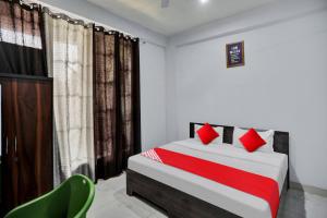 Un dormitorio con una cama con almohadas rojas y una silla en Collection O Mount Olympus Hotel, en Indirapuram