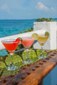 tres cócteles sentados en una mesa cerca del océano en Hotel Isla Del Pirata en Isla del Pirata