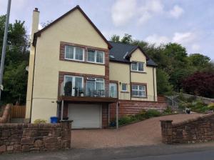 a large house with a balcony on a driveway at Stonewater House Vegan Bed and Breakfast in Lamlash