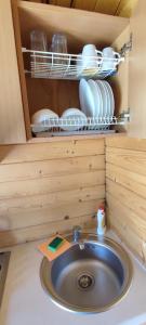 a sink in a cabinet with plates and dishes at Pas Jūratę namelių nuoma Šventojoje in Šventoji