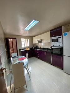 cocina con mesa de cristal y armarios morados en appartement rabat agdal, en Rabat