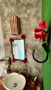 a bathroom with a sink and a mirror and red flowers at Village as casinhas in Uruçuca