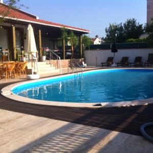 a large blue swimming pool with a table and chairs at Dardanos Pension in Hamidiye