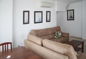a living room with a brown couch and a table at Apartamentos Turísticos Fercomar in Nerja