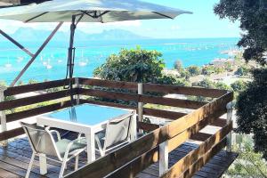 einen Tisch und Stühle auf einer Terrasse mit einem Sonnenschirm in der Unterkunft Chez Charlotte et Axel in Punaauia