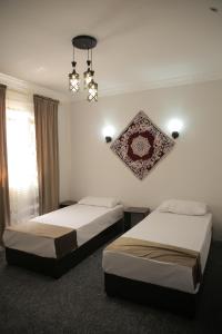 two beds in a hotel room with a chandelier at Rasul-Nazar in Khiva