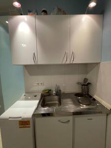 una piccola cucina con lavandino e armadietti bianchi di Hause münchen comfort! a Monaco