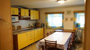 eine Küche mit gelben Schränken und einem Tisch mit Stühlen in der Unterkunft Holiday House Mária in Závažná Poruba