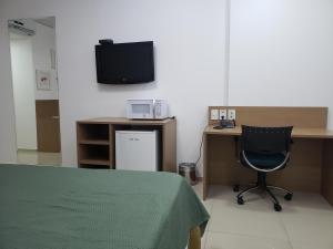um quarto com uma secretária, uma cadeira e uma televisão em Apto Hotel Blue Tree Manaus em Manaus