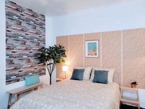 a bedroom with a large bed and a brick wall at Cosy Case proche Paris Montmartre in Saint-Ouen