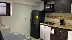 eine Küche mit einem schwarzen Kühlschrank und einer Mikrowelle in der Unterkunft Apartamento cerca helipuerto angar M45 Azotea in Medellín