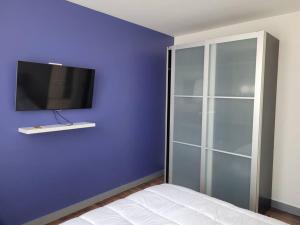 1 dormitorio con una pared azul y TV. en Maison en centre ville, en Cormeilles-en-Parisis