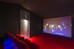 a cinema room with a large screen and red carpet at Le Domaine de la Roche Bernard Jacuzzi, piscine & Sauna 