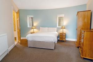 a bedroom with a white bed and two lamps at Downings Coastguard Cottages - Type B-E in Downings