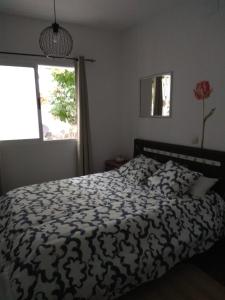 1 cama con edredón blanco y negro y ventana en El Regocijo Bajo en Oliva de la Frontera