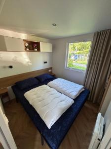 a large bed in a room with a window at DS Chalets-Simonsgat 63-Geweldige 6 tot 7 persoons chalet met 2 badkamers-vakantiepark Lauwersoog-aan het Lauwersmeer in Lauwersoog