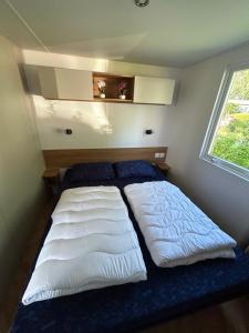 a large bed in a small room with a window at DS Chalets-Simonsgat 63-Geweldige 6 tot 7 persoons chalet met 2 badkamers-vakantiepark Lauwersoog-aan het Lauwersmeer in Lauwersoog