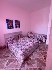 a bedroom with two beds in a room with pink walls at APPARTAMENTO MAESTRALE in Balestrate
