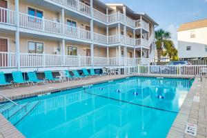 a swimming pool in front of a building with blue chairs at Surfside Beach Condo with Ocean Access and Balcony! in Myrtle Beach