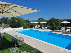 a swimming pool with chairs and a table and an umbrella at Agriturismo Il Casolare Di Nonno Mario in Manoppello