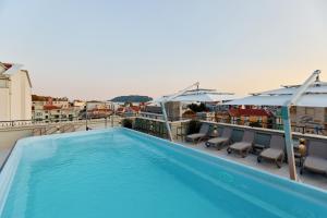 a pool on the roof of a building with chairs and umbrellas at Hotel Diplomat by Aycon in Budva