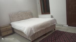 a bedroom with a white bed and a rug at Hamza Nezir malikanesi (Hane) in Trabzon