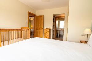 a bedroom with a white bed and a crib at Bradleys Cottage Creeslough in Creeslough