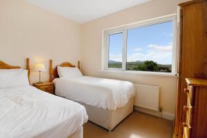 a bedroom with two beds and a large window at Bradleys Cottage Creeslough in Creeslough
